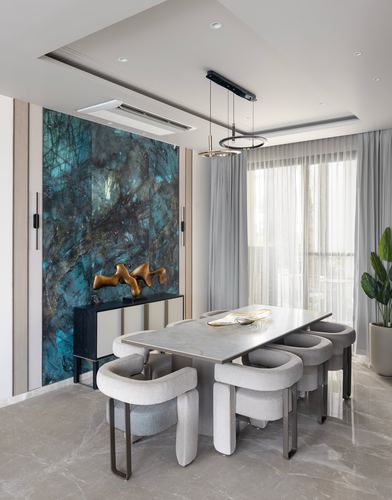 Dining room with teal stone accent wall, gold sculpture, round-back boucle chairs and marble table
