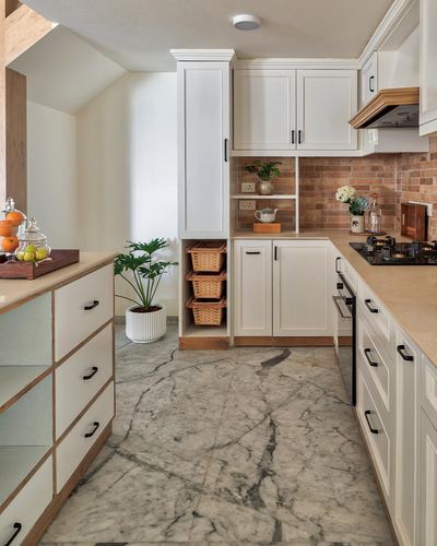 White farmhouse-style kitchen with terracotta backsplash, wicker basket storage and veined stone floor