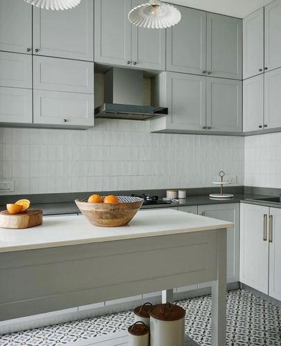 Grey shaker-style kitchen with island, wooden fruit bowl, and patterned tile floor