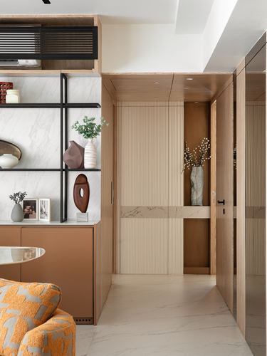 Foyer with marble shelving wall, fluted wood door with stone inlay, and copper-toned cabinetry