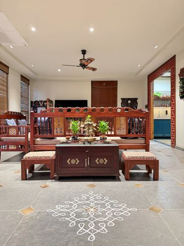 Traditional carved wood living room with kolam design on stone floor, Vijayawada home