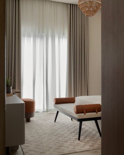 Bedroom vignette seen through doorway with leather bench, sheer curtains, rattan pendant light
