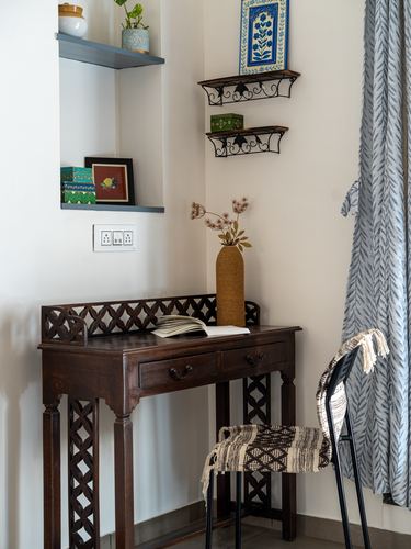 Dark wood console table with jaali fretwork legs beneath floating shelves and blue-and-white artwork