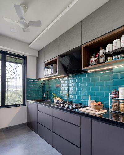Galley kitchen with grey cabinetry, teal tiled backsplash, and open wooden shelving near a window