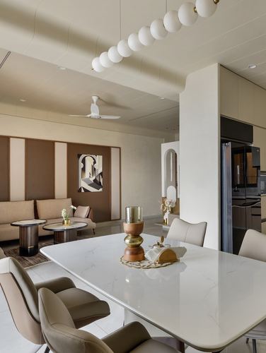 Open-plan dining and living space with marble-look table, globe pendant lights, and panelled wall art