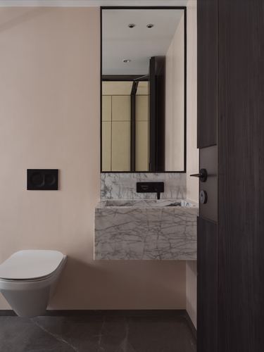 Pink powder room with floating marble vanity, wall-mounted toilet, and tall black-framed mirror