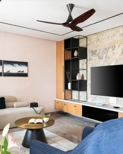 Living room with pink wall, black shelving, stone accent wall, and blue sofa