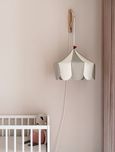 Fabric tent-shaped pendant lamp hanging on wall hook above white crib in nursery