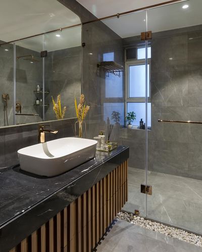 Modern bathroom with black marble vessel sink counter, ribbed wood cabinetry, and glass shower with gray stone tiles