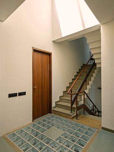 Foyer with wooden door, glass block floor inset, and staircase lit by overhead skylight