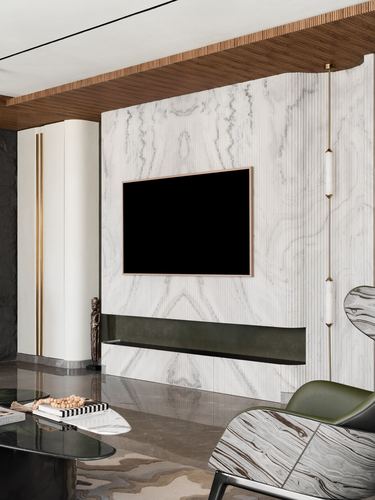 Living room with fluted marble-look TV wall, wood ceiling, green leather chair and pendant light