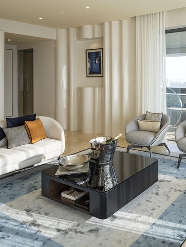 Living room with black coffee table, cream sofa, curved fluted drapery wall, and framed art