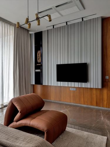 Living room with fluted grey TV panel, wood base, and curved rust leather chaise chair