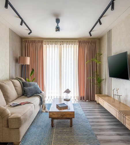 Narrow living room with beige sofa, striped rug, wooden console and fluted panelling by window