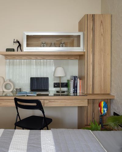 wood-panelled study nook with desk, laptop, lamp and folding chair beside a bed