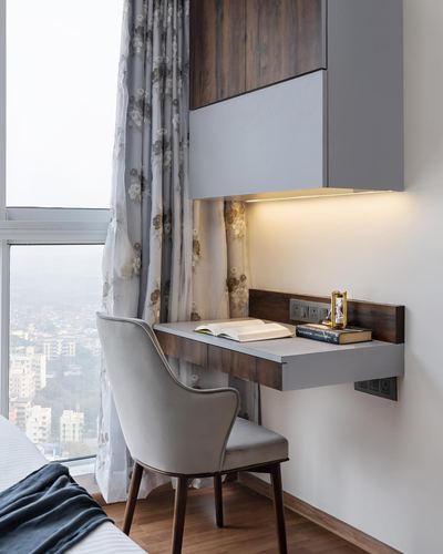 Floating wood desk with chair by window overlooking city skyline in high-rise apartment
