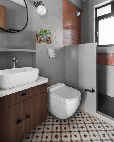 Grey concrete bathroom with wood vanity, wall-hung toilet, and patterned floor tile leading to shower.