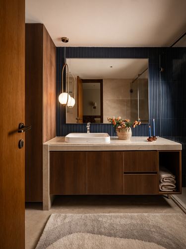 Bathroom vanity with wood cabinetry, stone counter, vessel sink and fluted navy tile wall