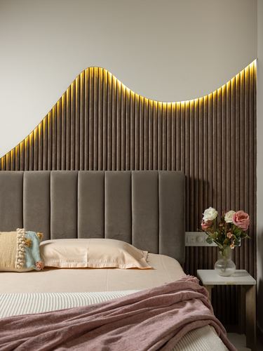 Grey velvet channel headboard beneath a curved backlit wooden fluted wall panel