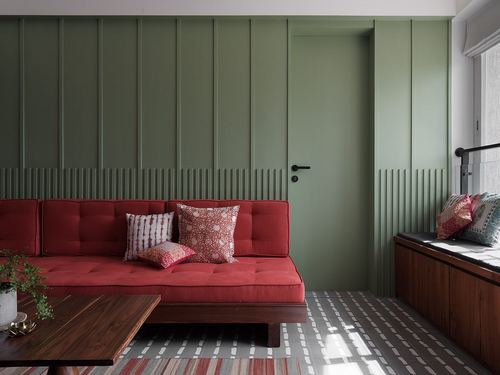 Green paneled living room with red tufted daybed and patterned tile floor