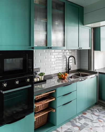 Teal kitchen cabinetry with white beveled subway tile, black fixtures, and terrazzo flooring