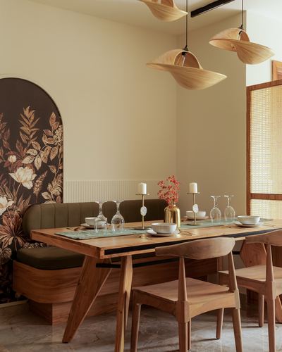 Wooden dining table with cone pendant lights beside an arched floral mural niche