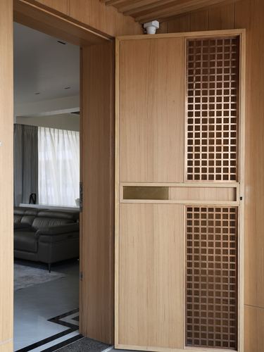 Wood-panelled entrance door with lattice grille and brass strip, living room visible beyond