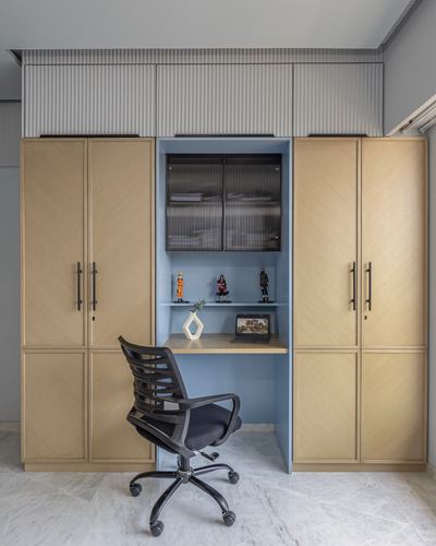 Built-in wardrobe with fluted panels opens to reveal a blue study nook with desk and chair