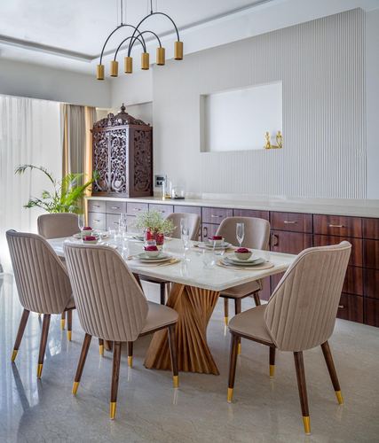 Dining room with marble-top table, spiral wood base, beige chairs, and carved wooden cabinet