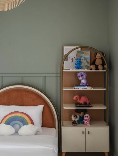 Child's bedroom corner with arched terracotta bed and matching arched shelf full of toys