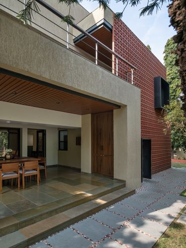 House exterior with terracotta jaali screen, wooden slat ceiling, and stone paved entrance path