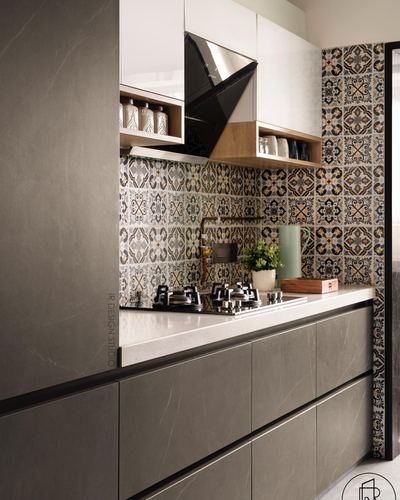 Grey stone kitchen counter with black hob against patterned tile backsplash and angular chimney hood