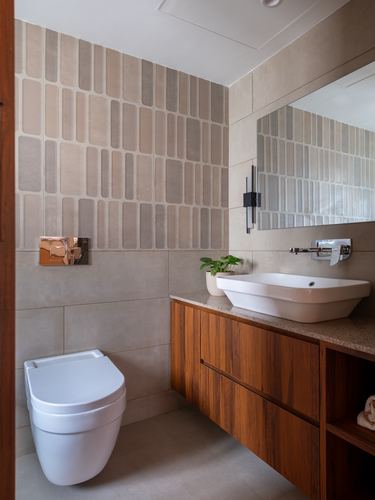 Modern bathroom with textured tile wall, wood vanity, vessel sink, and wall-hung toilet