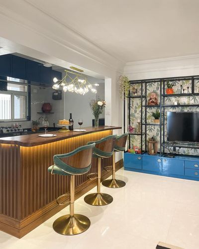 Kitchen island with fluted wood front and teal velvet brass stools facing an open shelving unit and blue console