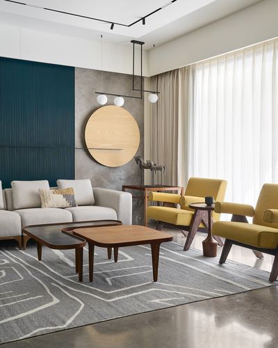 Living room with teal fluted wall, round wood disc art, mustard armchairs and nesting wood coffee tables