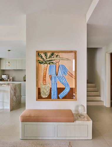 Entryway with a striped-figure painting above a pink bench and marble table lamp.
