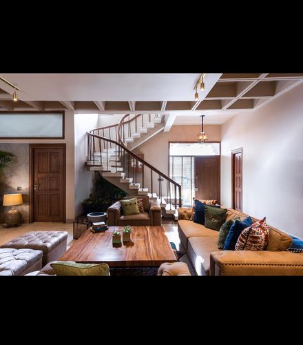 Living room with tan leather sofa, live-edge wood coffee table, and curved staircase behind