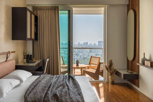 Bedroom with cane cabinet, wood floor, and glass door opening to balcony overlooking city skyline