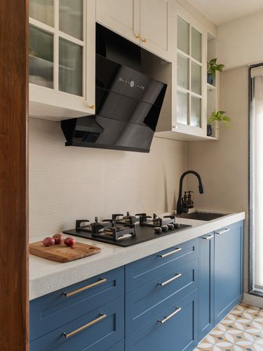 Blue and white kitchen with black chimney hood over gas hob and patterned floor tiles