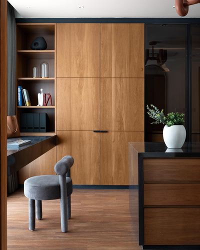 Wood-paneled study nook with open shelving, floating desk, and grey stool chair