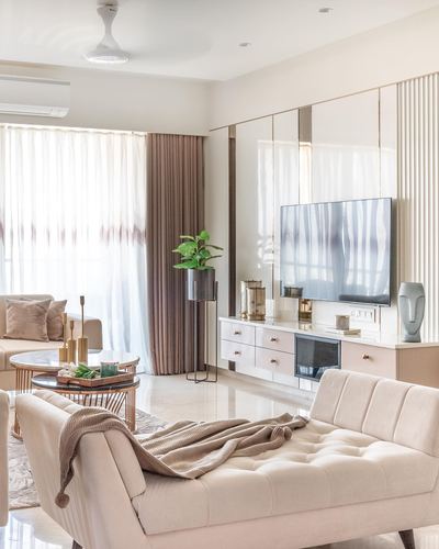 Blush-toned living room with tufted chaise, marble floor, and mirrored TV wall panelling