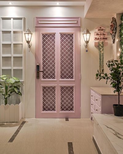 Pink lattice-glass entry door flanked by lantern sconces in a marble-floored foyer