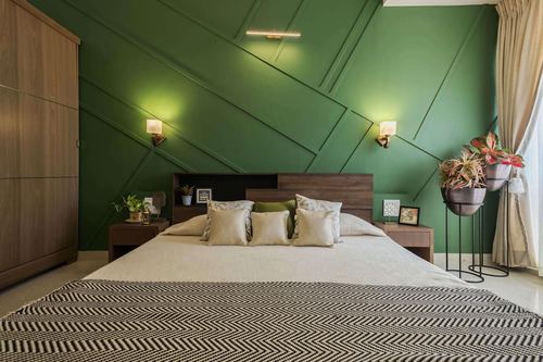 Bedroom with green geometric paneled wall, wood headboard, sconces and cream bedding