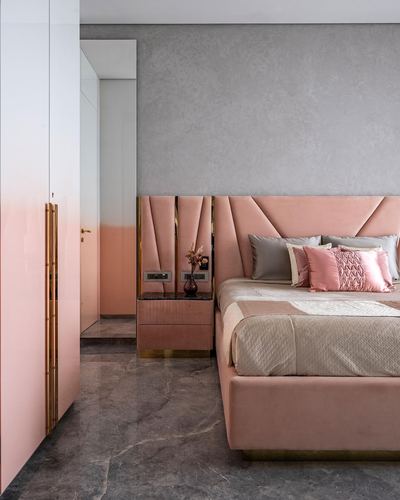 Pink velvet bed with faceted headboard beside pink lacquered wardrobe and marble floor