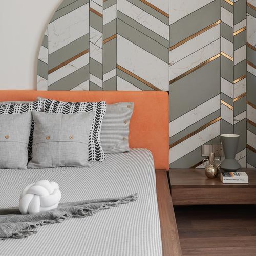 Bedroom with orange velvet headboard against arched chevron-patterned wall and wooden nightstand