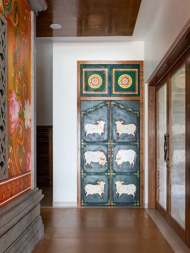 Hallway with hand-painted teal door depicting cows, flanking mural and stone wall, wood ceiling