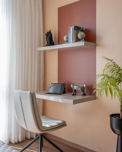 Floating white desk and shelf against a terracotta accent wall with decor and a chair
