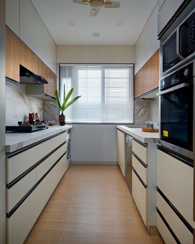 Symmetrical galley kitchen with cream cabinets, wood accents, marble backsplash and central window