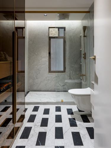 Marble bathroom with glass shower enclosure, wall-hung toilet, and geometric black-and-white floor tiles