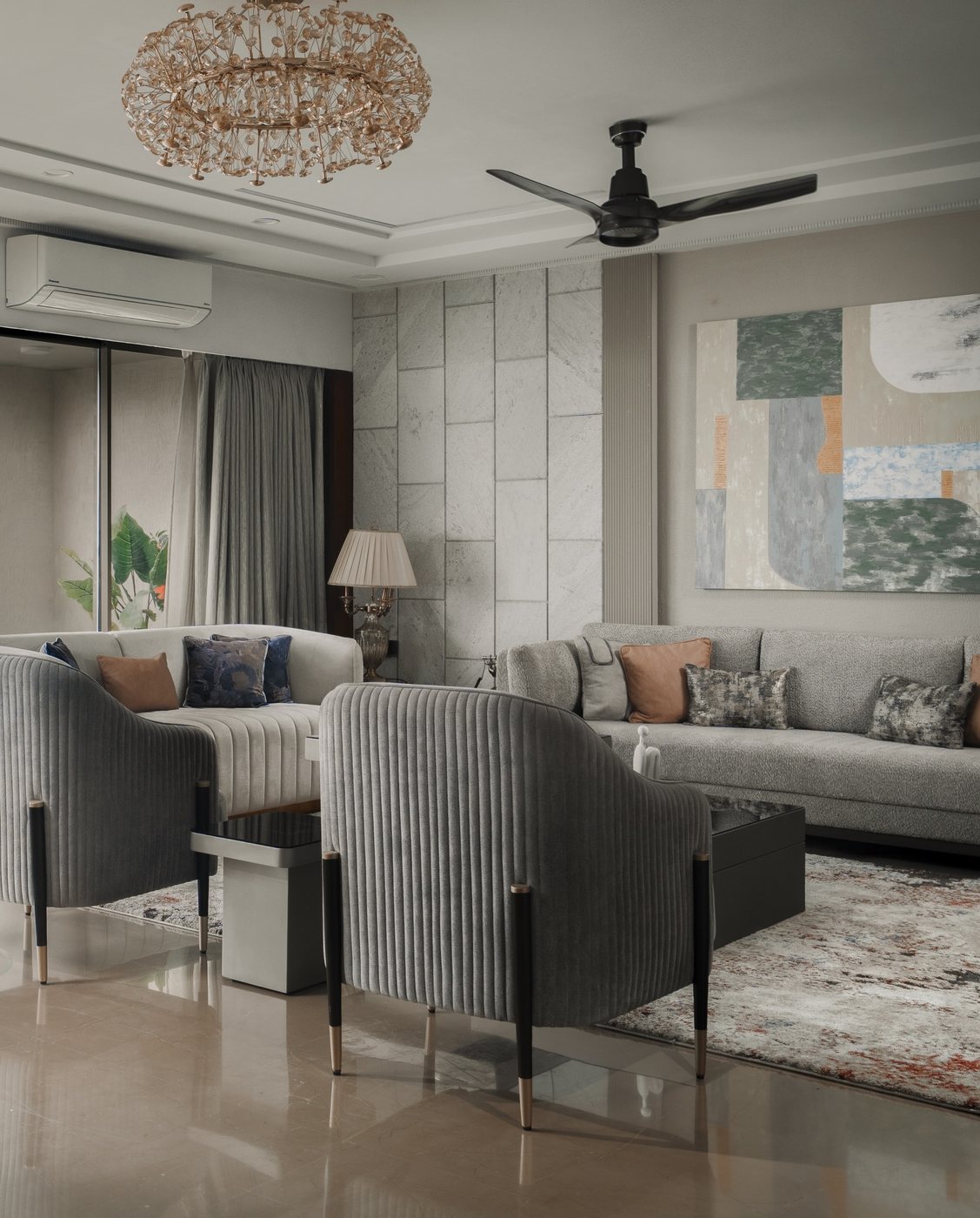 Grey living room with ribbed velvet armchairs, marble wall panel, and abstract art above sofa